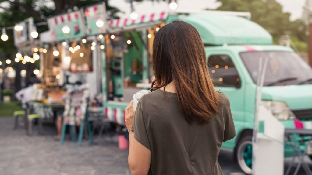 woman in front of a food truck back turned.